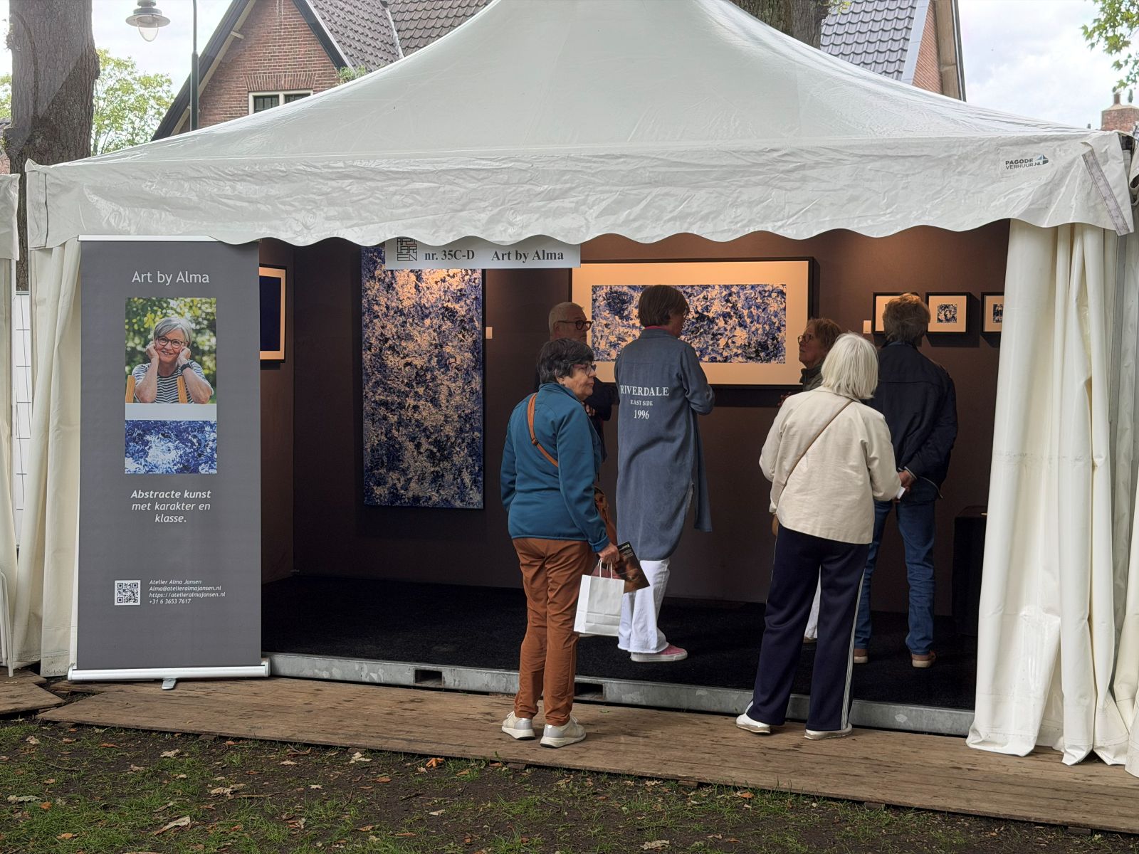 "Stand van Art by Alma tijdens Art Laren 2026 met abstracte schilderijen en bezoekers"