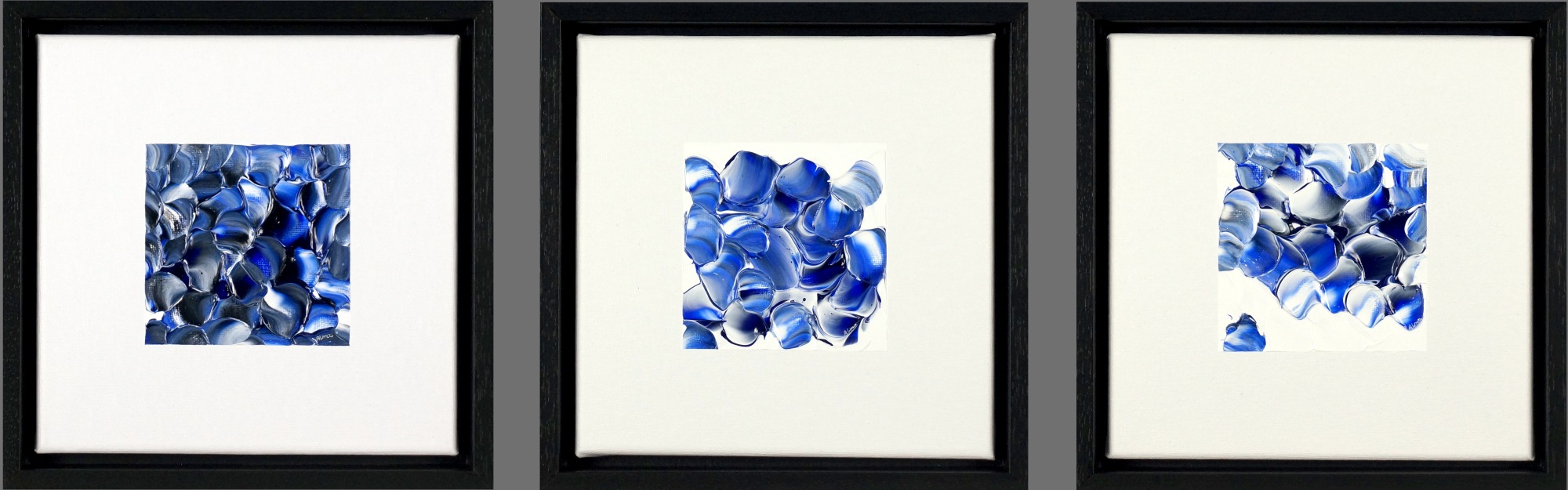 Drieluik Grijs/Blauw van Alma Jansen met drie abstracte schilderijen van 20 x 20 cm in grijze en blauwe tinten, gepresenteerd in zwarte baklijsten.